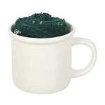 White mug filled with green powder on a white background