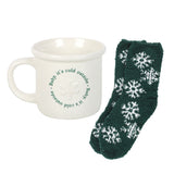 White mug with text and green socks with snowflake pattern on a white background