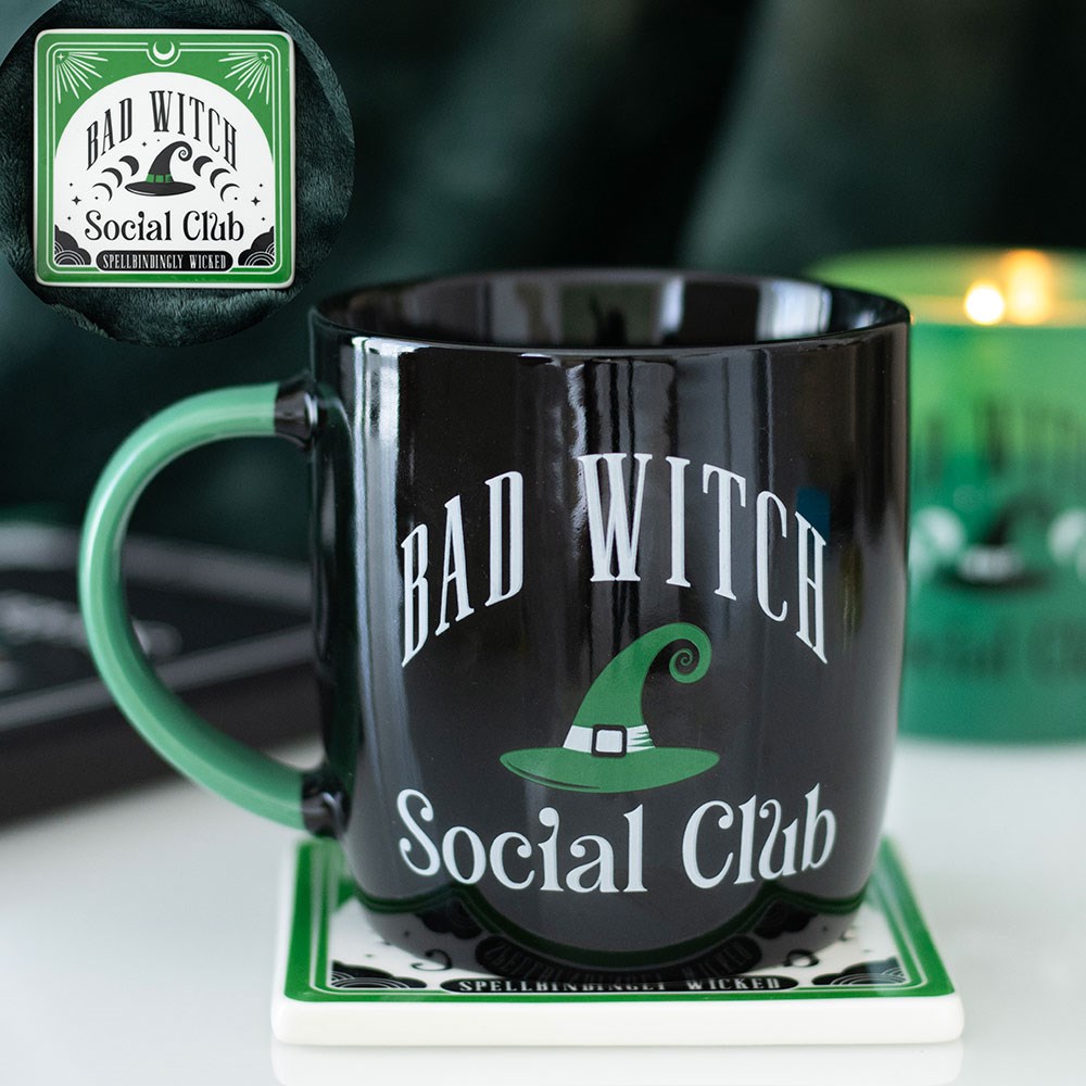 Black mug with 'Bad Witch Social Club' text and green witch hat design on a coaster, with 'Bad Witch Social Club' logo in top left corner.
