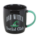 Black mug with 'Bad Witch Social Club' text and green handle on a white background