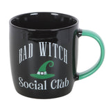 Black mug with 'Bad Witch Social Club' text and green handle on a white background