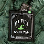 Black tote bag with 'Bad Witch Social Club' design on a green textured background