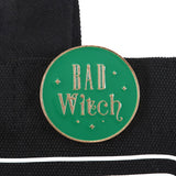 Green enamel pin with 'Bad Witch' text on a black background