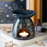 Decorative wax warmer with a lit candle on a surface with star-themed decor.