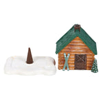 Small wooden cabin figurine with a snow-covered base on a white background