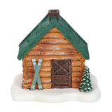 Decorative log cabin with green roof, skis, and a small tree on a white background