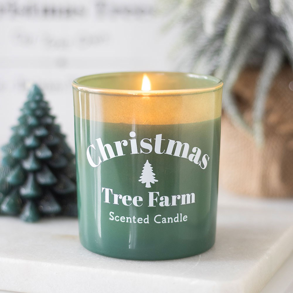 Green candle labeled 'Christmas Tree Farm Scented Candle' with a small decorative tree in the background.