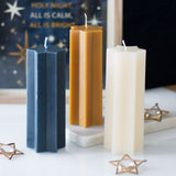 Three hexagonal candles in blue, gold, and white on a decorative background with stars and text.