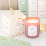 Pink candle labeled 'The Love Letter' with its packaging on a light surface.