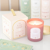 Pink candle labeled 'The Love Letter' with its packaging on a light surface.