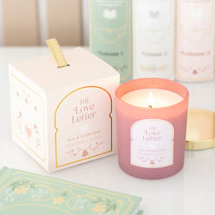 Pink candle labeled 'The Love Letter' with its packaging on a light surface.