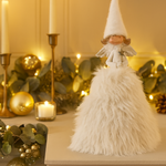 Decorative angel figure on a mantelpiece with candles and ornaments