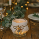 Decorative candle holder with a deer design on a wooden table with blurred lights in the background