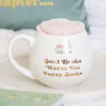 White mug with text 'Good Books Warm Tea Fuzzy Socks' on a white surface.