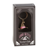 Keychain with a witch hat design in a 'Good Witch Social Club' packaging on a white background