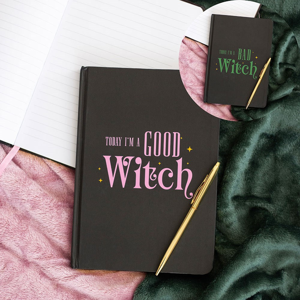 Black notebook with 'Today I'm a Good Witch' text on a pink surface with a green blanket.