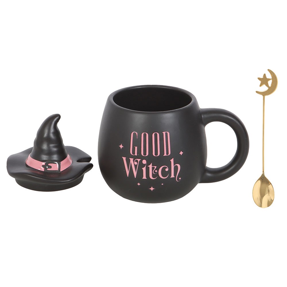 Black mug with 'GOOD WITCH' text, small witch hat, and gold spoon on a white background