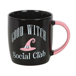 Black mug with pink handle featuring 'Good Witch Social Club' text and witch hat graphic on a white background.