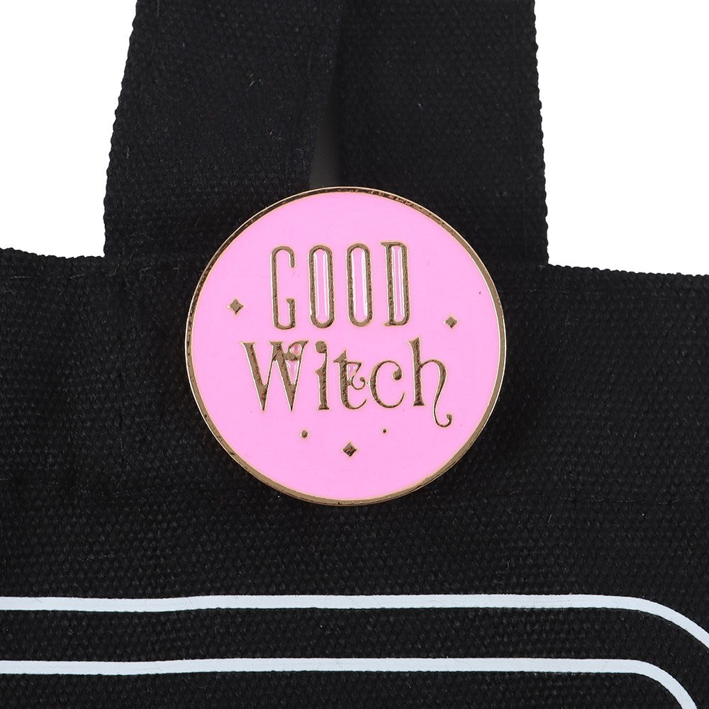 Pink 'Good Witch' enamel pin on a black bag