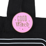 Pink 'Good Witch' enamel pin on a black bag