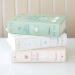 Stack of decorative books with pastel covers on a white surface