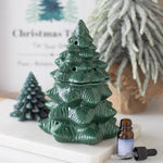Green ceramic Christmas tree with a bottle of essential oil on a white surface.