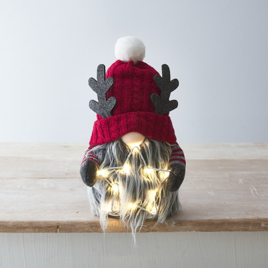 A whimsical figurine of a gonk with a red knitted hat and a fluffy pom-pom, featuring an LED star on its head.