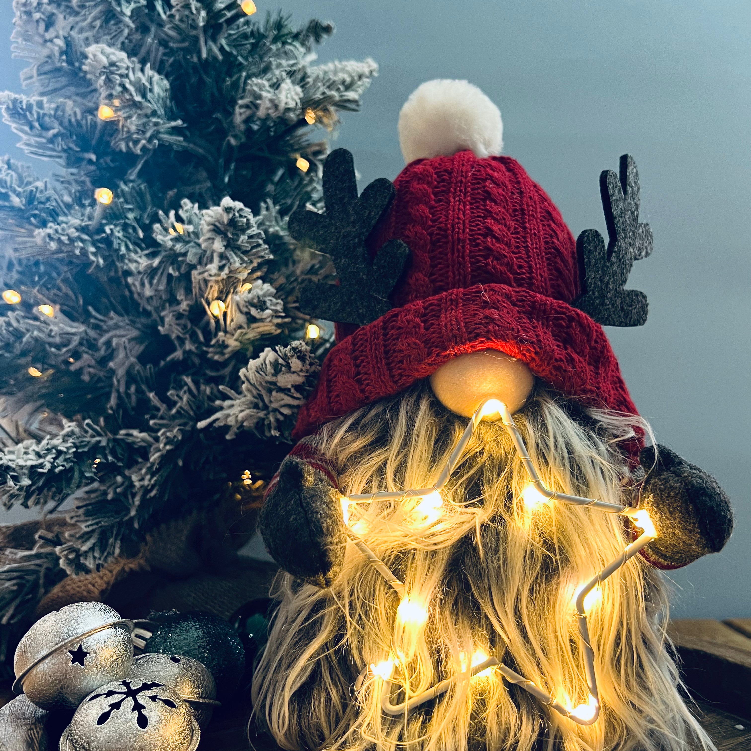A whimsical figurine of a gonk with a red knitted hat and a fluffy pom-pom, featuring an LED star on its head.