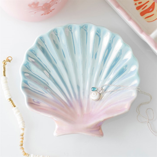 Shell-shaped jewelry dish with a necklace on a light background
