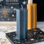 Hexagonal blue candle on a star-patterned card with a blurred background