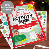 A personalised Christmas activity book with stickers for William, featuring a colorful cover with festive designs, placed on a table with decorations and assorted Christmas-themed stickers.