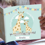 A personalised story book titled 'Big Sister', featuring illustrations of giraffes and a banner with the name 'Amelia' on it, held open by a person.