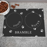 Black personalised pet bowl mat, with a bowl full of dog treats to the side 