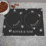 Black personalised pet bowl mat, with a bowl full of dog treats to the side 