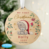 A round wooden decoration featuring an illustration of a teddy bear with a Santa hat, surrounded by Christmas-themed elements like stars, berries, and the text 'My First Christmas'. 01