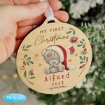 A round wooden decoration featuring an illustration of a teddy bear with a Santa hat, surrounded by Christmas-themed elements like stars, berries, and the text 'My First Christmas'. 02