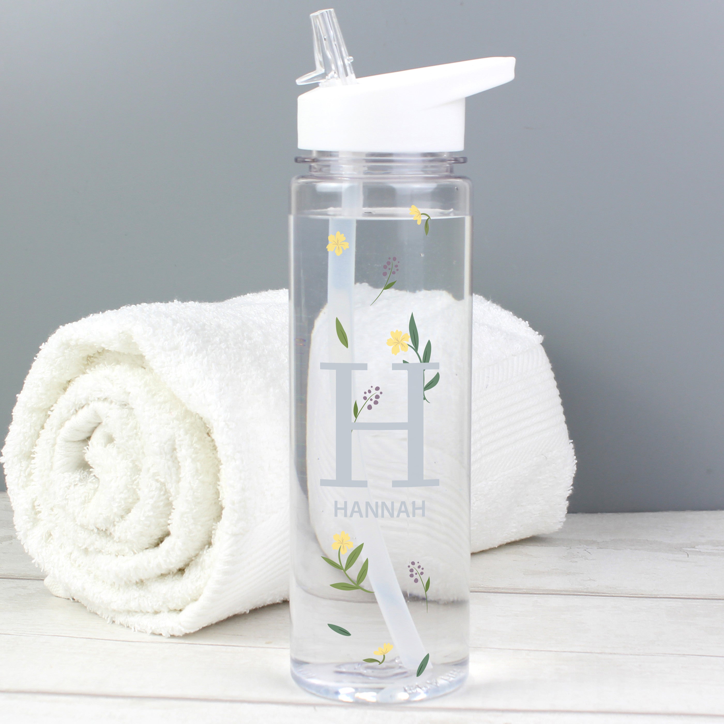 A clear plastic water bottle with a white twist-on lid and a personalised floral design with the initial 'H' and the name 'Hannah'.