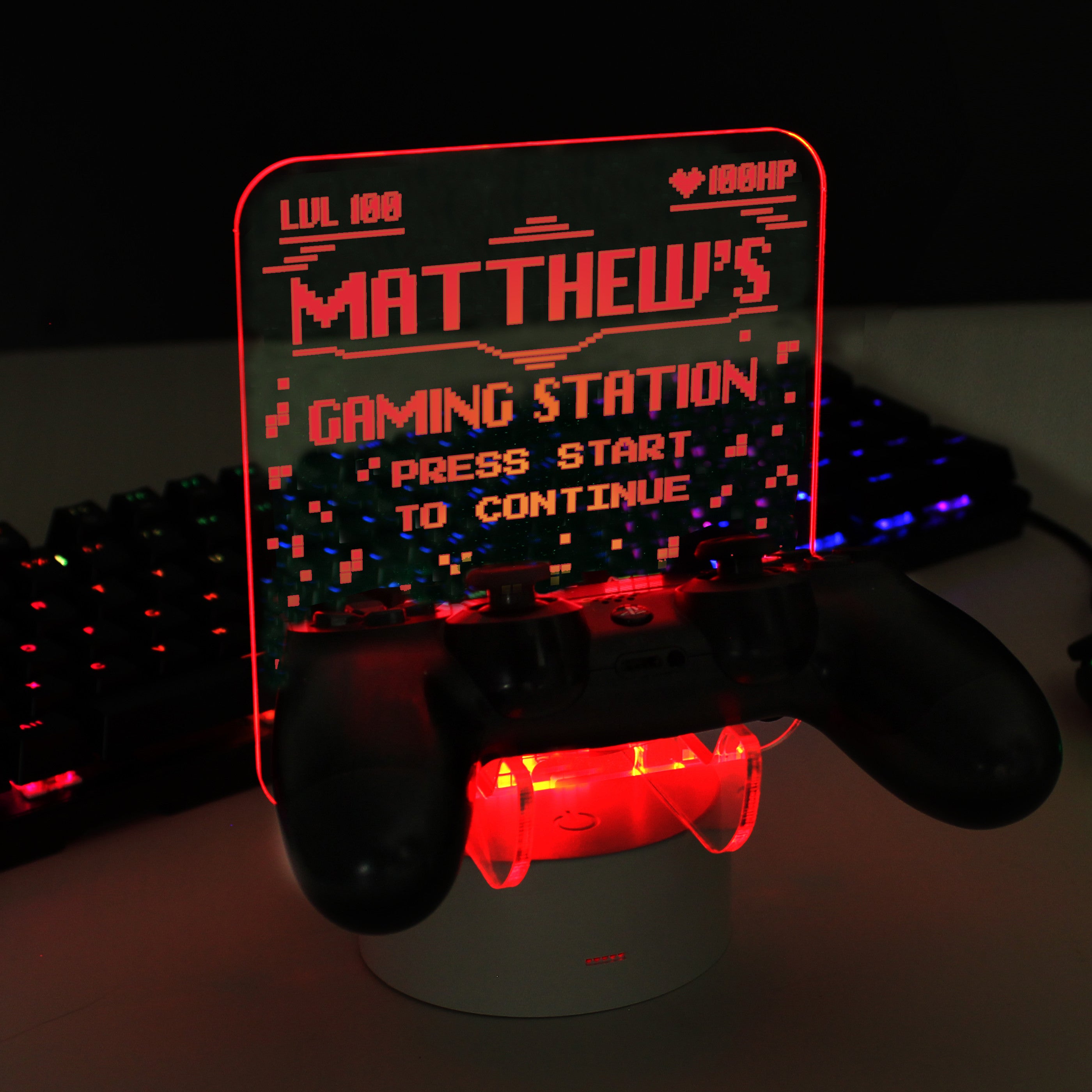 Personalised gaming controller holder with LED colour changing light, displaying a name and gaming-related phrases on a illuminated panel.