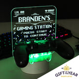 Personalised gaming controller holder with LED colour changing light, displaying a name and gaming-related phrases on a illuminated panel.