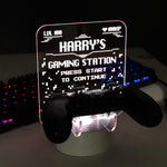 Personalised gaming controller holder with LED colour changing light, displaying a name and gaming-related phrases on a illuminated panel.
