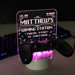 Personalised gaming controller holder with LED colour changing light, displaying a name and gaming-related phrases on a illuminated panel.