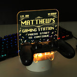 Personalised gaming controller holder with LED colour changing light, displaying a name and gaming-related phrases on a illuminated panel.