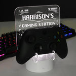 Personalised gaming controller holder with LED colour changing light, displaying a name and gaming-related phrases on a illuminated panel.