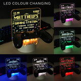Personalised gaming controller holder with LED colour changing light, displaying a name and gaming-related phrases on a illuminated panel.