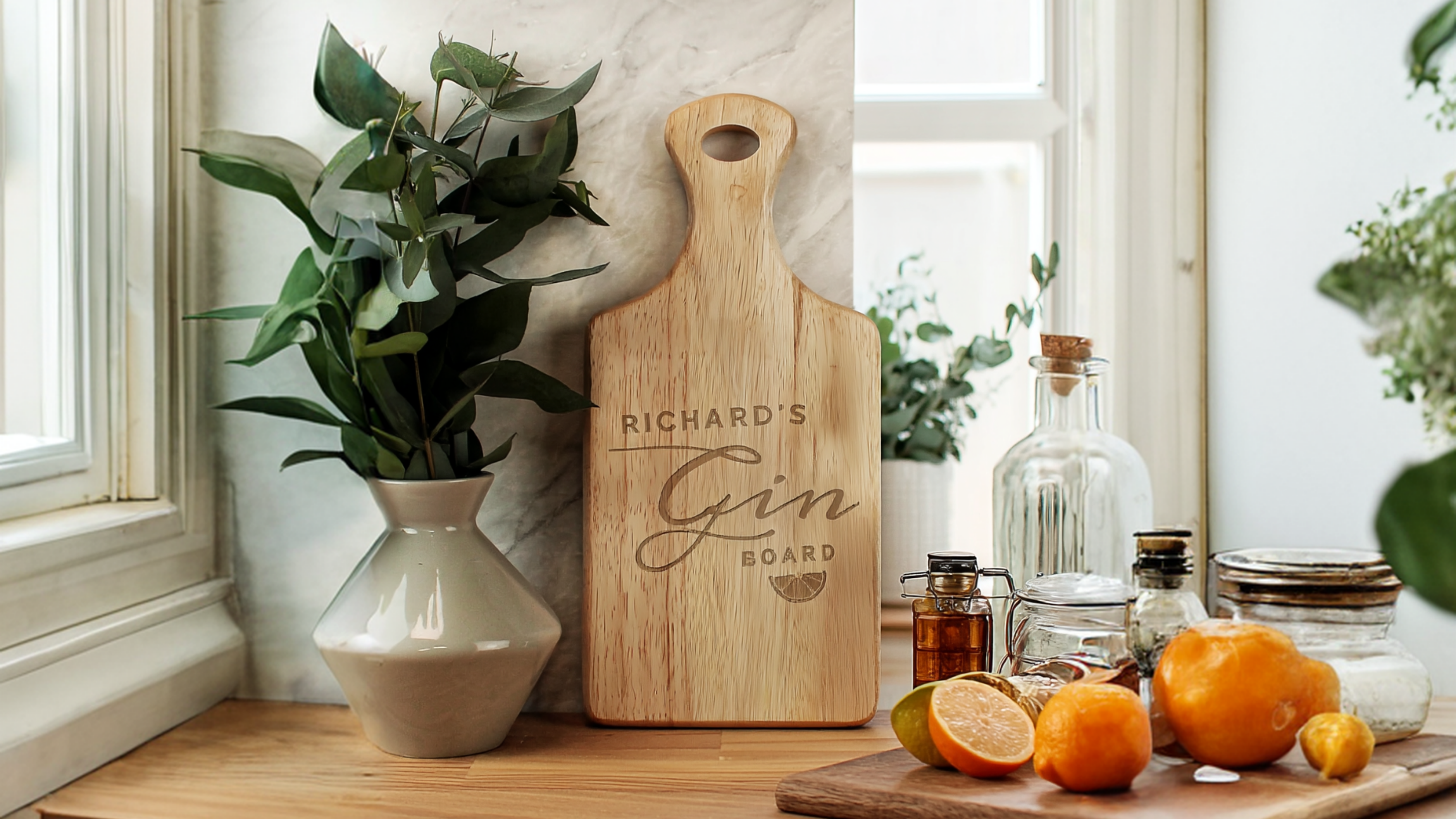 Personalised Gin Wooden Paddle Board cutting board with 'Richard's Gin Board' engraved, next to a vase with greenery and oranges on a wooden surface.