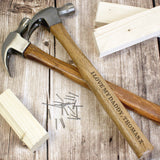 A personalised hammer with a wooden handle and metal head, engraved with the text 'Daddy', along with a few nails and pieces of wood scattered around it.