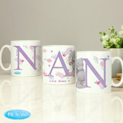 Three ceramic mugs with 'Nan' written on each, featuring floral and animal designs, placed on a table with a 'Me To You' logo in the corner.