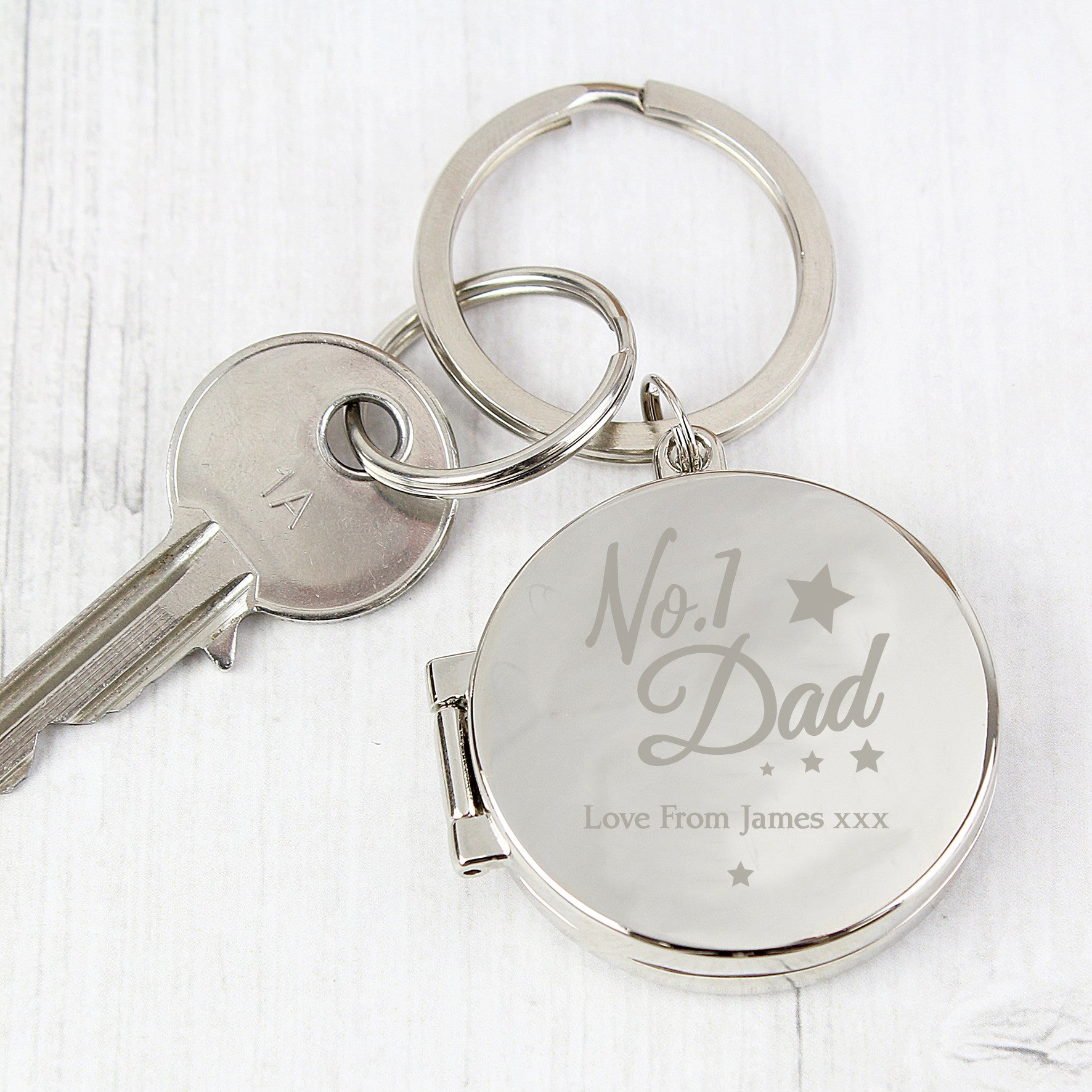 A silver-colored keyring with 'No.1 Dad' inscribed on it alongside a personal message 'Love from James Xx'.