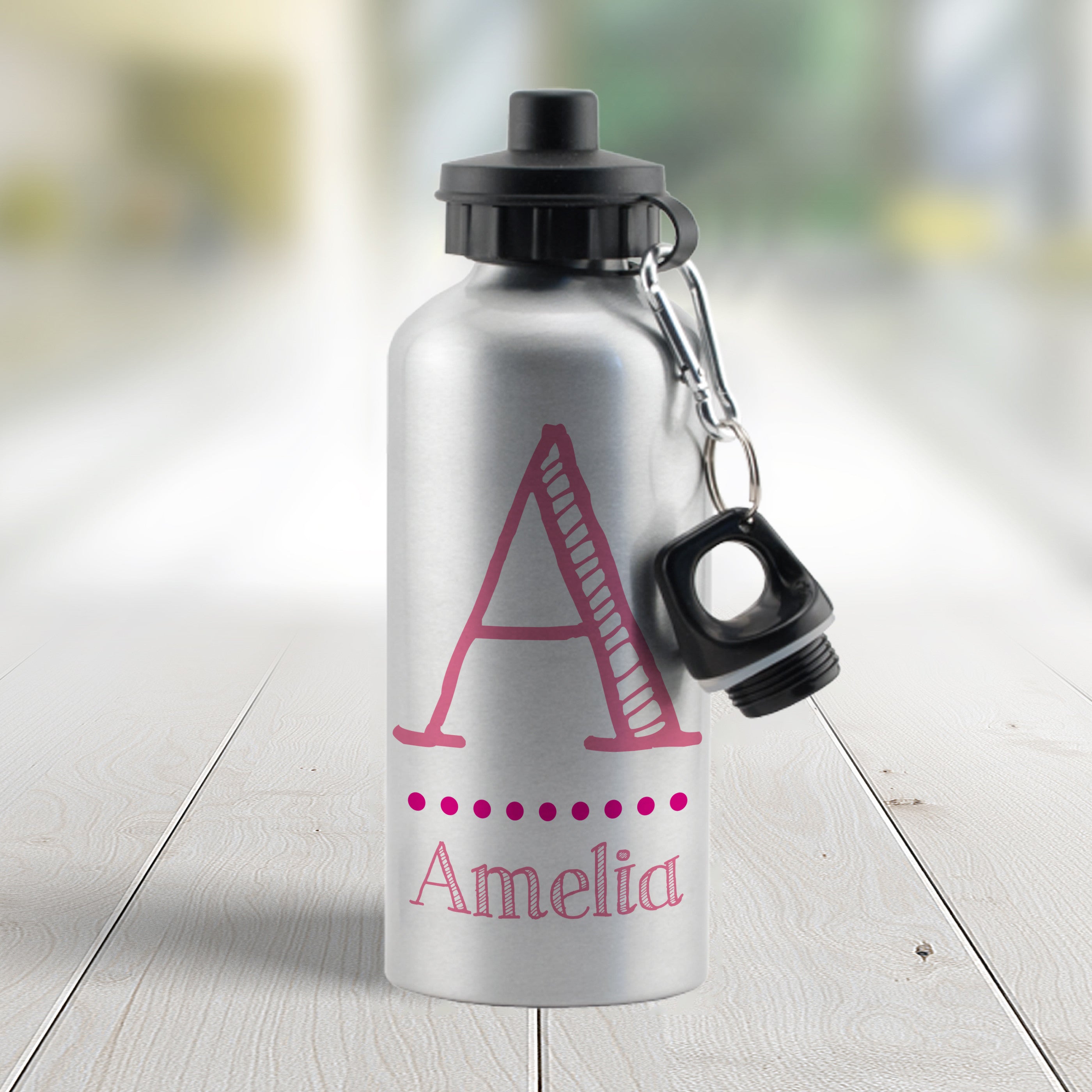 A silver aluminum drinks bottle with a black lid and a strap, personalized with the name 'Sarah' in pink.