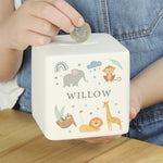 A white ceramic square money box with a personalised name 'Arthur' and a jungle animal theme, featuring illustrations of an elephant, giraffe, monkey, lion, and zebra.